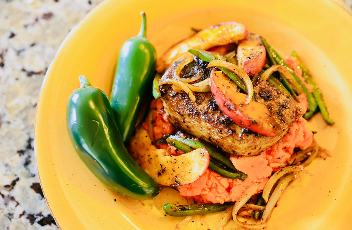 Pork chops and apples on a yellow plate with whole jalapeno peppers