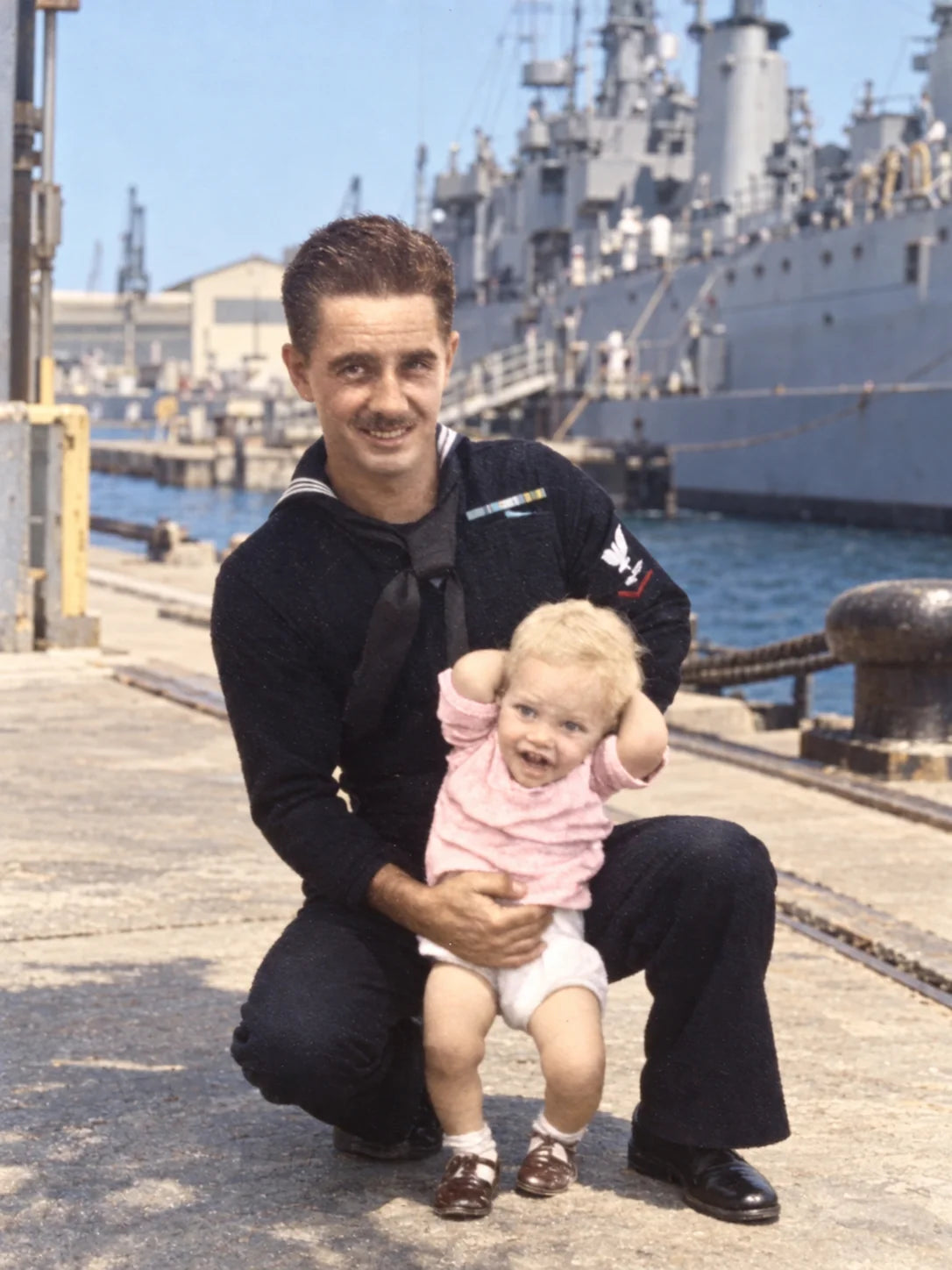 A photo of Popie and his dad in Navy uniform in front of a ship