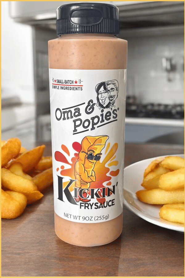 An image of a bottle of Oma & Popie's Kickin' Fry sauce on a kitchen counter next to a plate of fries