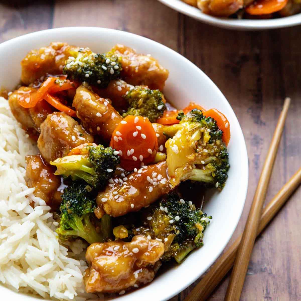 White bowl with Spicy Chicken, rice and veggies in a asian sauce.