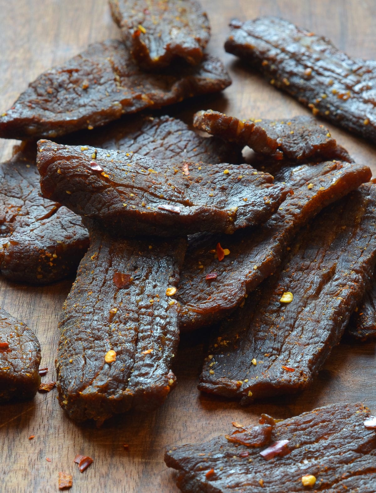 Strips of Beef Jerky on a cutting board with pepper flakes