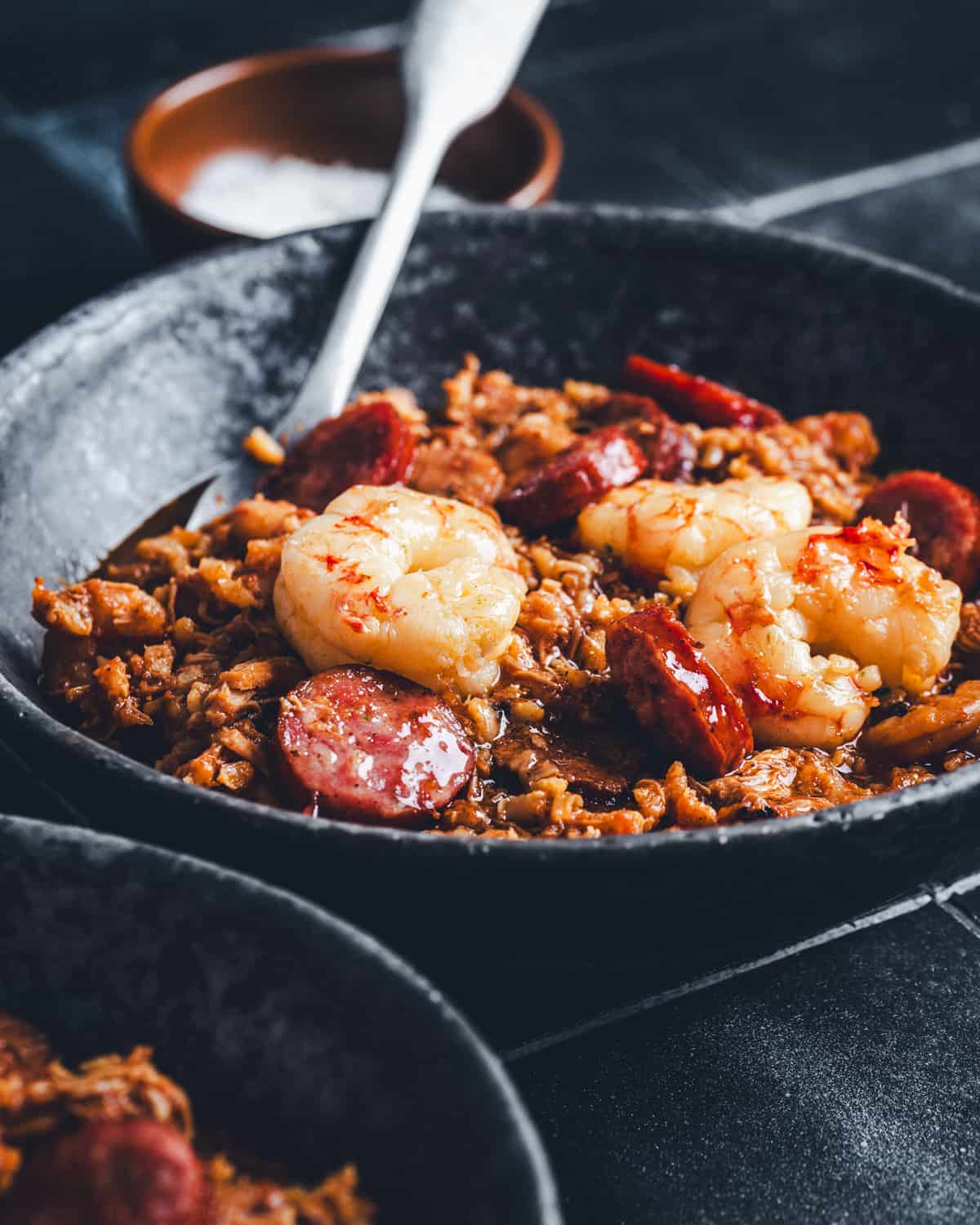 Black bowl with Jambalaya - pieces of shrimp, sausage on a bed of brown rice
